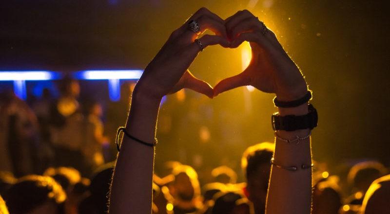 Handen die een hartvorm maken bij een concert ontdekt via websites voor evenementenboeking